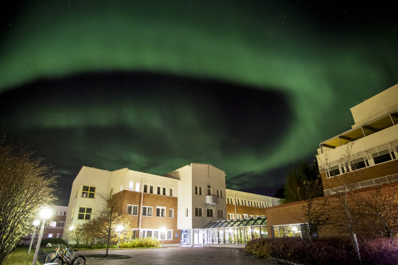 The University of Lapland in night-time. Northern lights shine over the campus.