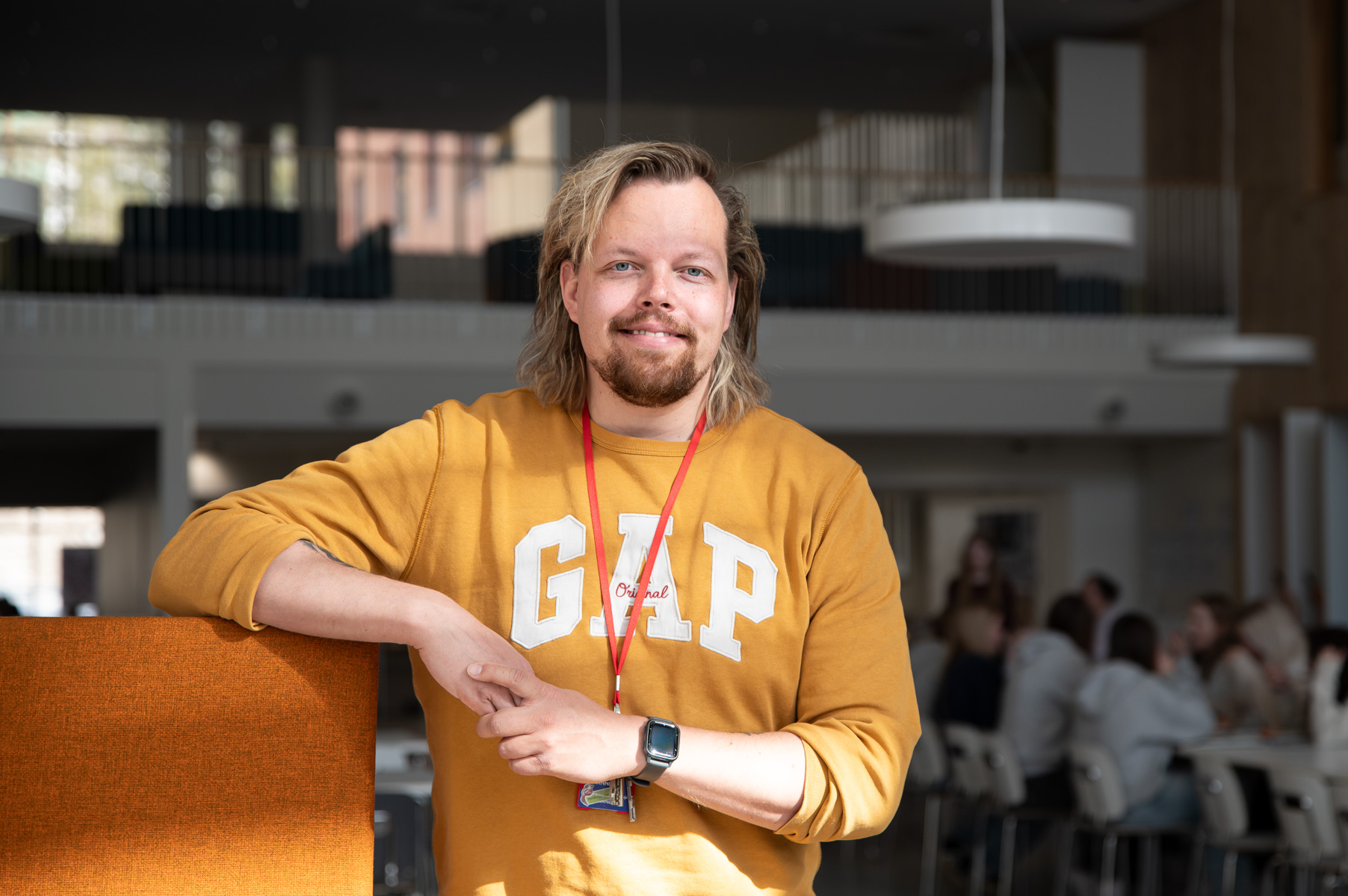 Keltapaitainen mies Ounasrinteen koulun ruokalassa hymyilee.