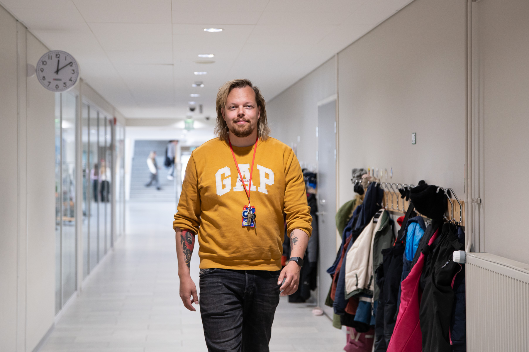 Keltapaitainen mies kävelee koulun käytävällä.