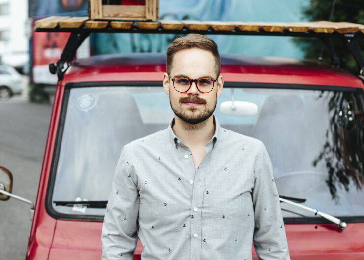Mies auton edessä kauluspaidassa.